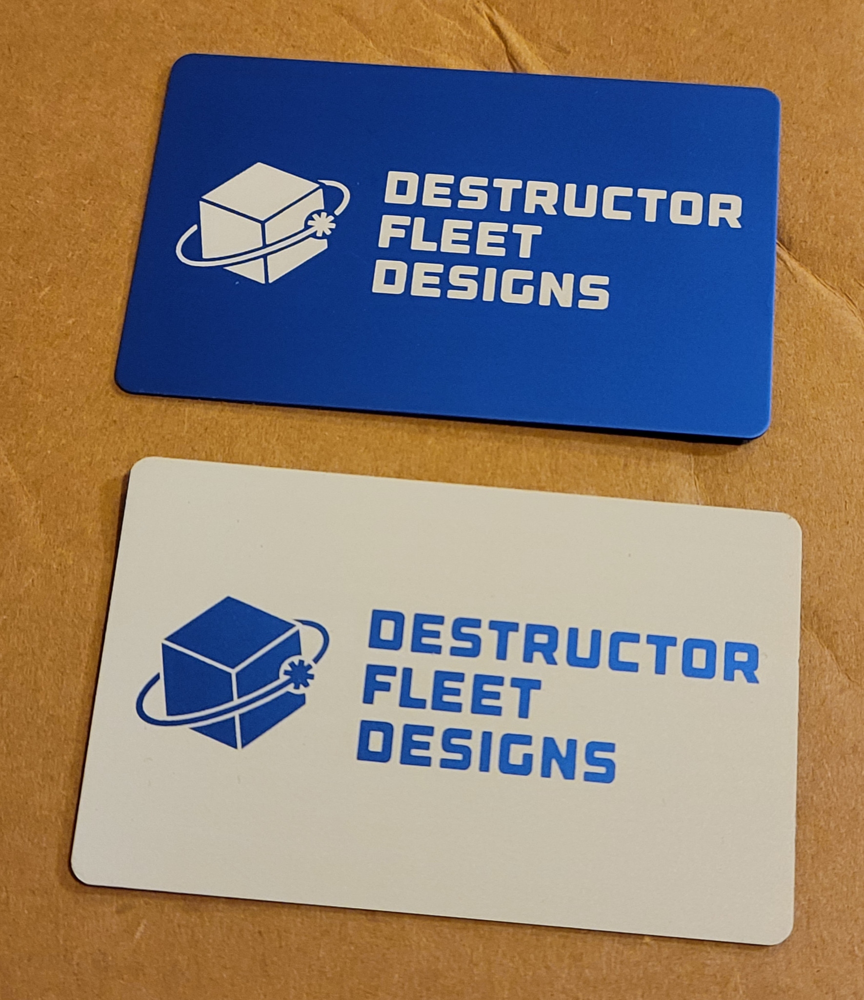 Two anodized aluminum parts engraved with the Destructor Fleet Designs logo